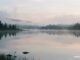 Klidné jezero za úsvitu s jemnou mlhou a hladkou hladinou