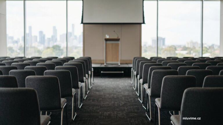 Prázdný konferenční sál s řadami židlí a řečnickým pultem